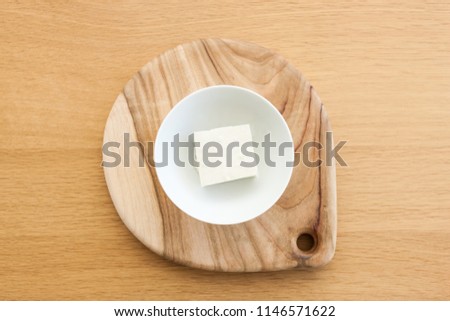  a piece of tofu in the bowl on the wood table