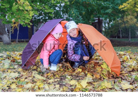 Autumn, little girls hid under umbrellas,Toddler girl outdoors at rainy day