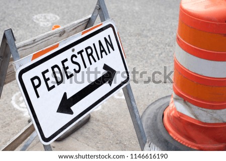 Close up on a Pedestrian Crossing sign with arrows at a sidewalk construction site with, space for text on the right