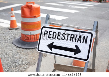 Close up on a Pedestrian Crossing sign with arrows at a sidewalk construction site, with space for text on the left