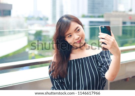 Asian beautiful girl taking a selfie on rooftop's department store in Bangkok, Thailand