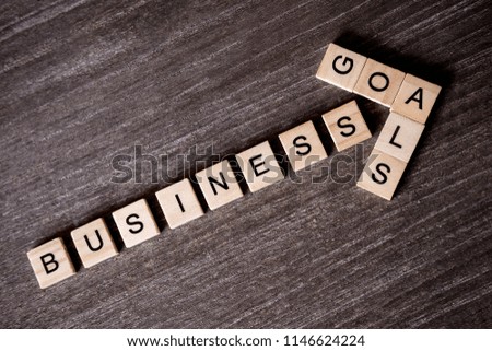 Concept presented by crossword with words business success to goal with wooden cubes on wooden background.