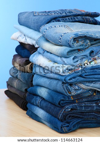 Many jeans stacked in a piles on blue background
