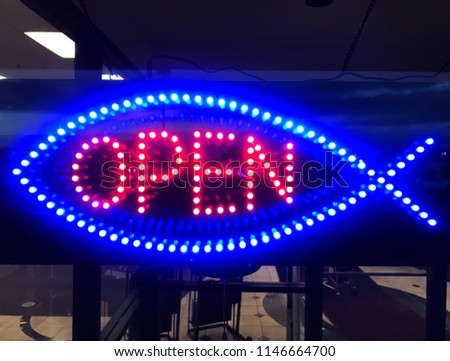 Red Neon "Open" Sign surrounded by blue neon lights resembling a fish. 