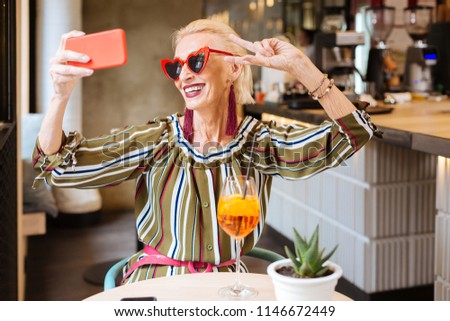 Great mood. Cheerful happy woman smiling while taking a photo of herself