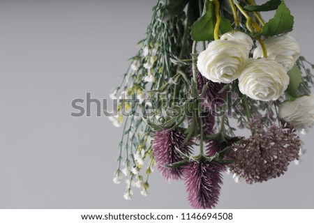Woman hand holding bouquet of fresh flowers on light background.
