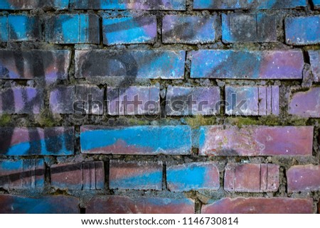 an old crumbling red brick wall covered in colored graffiti with spray paints. High resolution photo