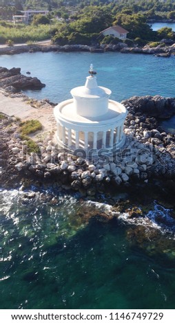 Aerial drone photo of iconic Agioi Theodoroi doric column lighthouse built in a small peninsula with beautiful scattered clouds , Argostoli, Cefalonia, Ionian, Greece