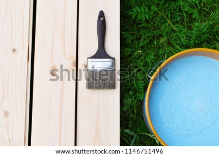 Blue paint in can and brush on wooden planks ready for painting or priming with waterborne exterior wood preservative for timber protection top view on grass background. Home improvement concept. 
 Royalty-Free Stock Photo #1146751496