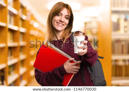 Student woman holding a cup of coffee on unfocused background