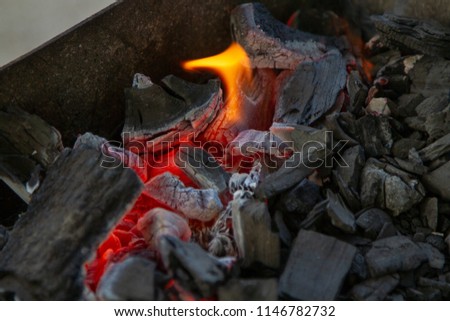 Bright red-hot coals and a hot flame in the brazier. Photo of the grill. A bright hearth of fire. Heart of fire. Hot temperature in the grill.