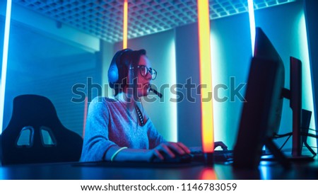 Low Angle Shot of the Beautiful Friendly Pro Gamer Girl Playing in Online Video Game and Streaming it, Wearing Headset Talks with Her Fans and Team into Headphones Microphone. Background Neon Retro.