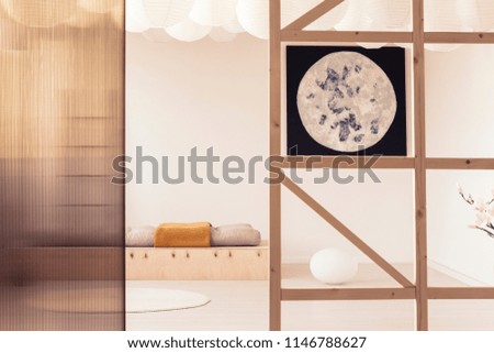 Poster and screen in white minimal bedroom interior with pillows on wooden bed. Real photo