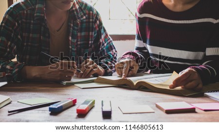 Asian young man and woman sitting pointing studying examining, Tutor books with friends Young students campus helps friend catching up and learning. People learning education Royalty-Free Stock Photo #1146805613