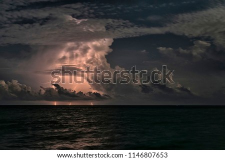 Flashing lightnings through the clouds above the night sea.