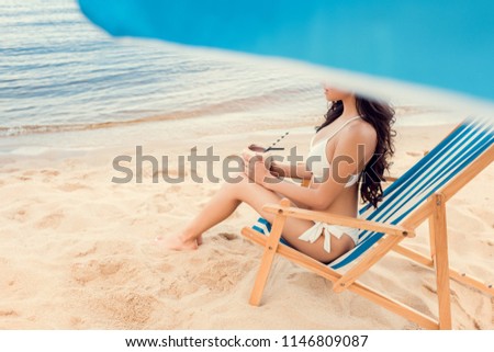attractive girl sitting on beach chair with coconut cocktail