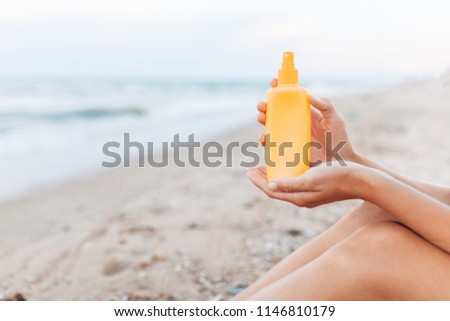 Beautiful girl, sun cream application, on the beach, feet close-up, jar of sun cream