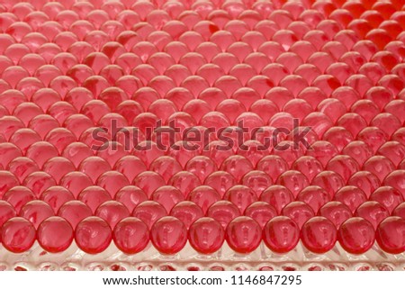 large group of red hydrogel spheres lined on a glass