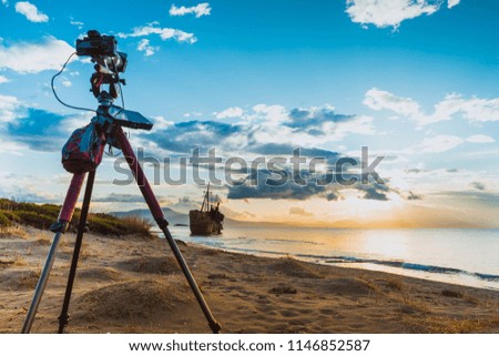Professional camera on tripod taking picture film video from greek coastline with rusty shipwreck Dimitrios near Gytheio, Gythio Laconia Peloponnese Greece.