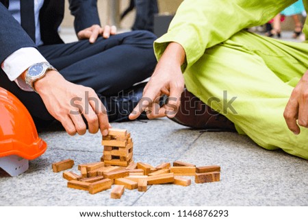 The business team and engineers plays wood game that compares how to co-operation between business team and engineers build the building together. 
Photo concept business team and engineers.