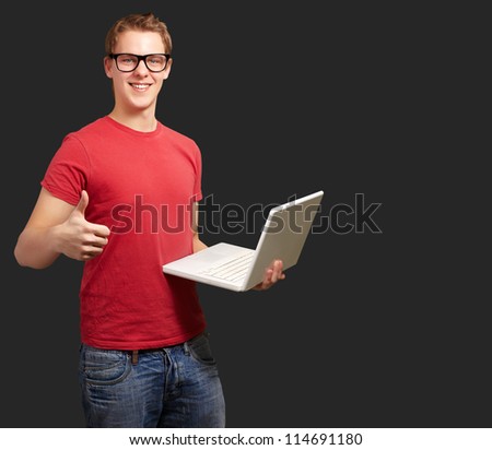 Man holding laptop with thumbs up isolated on gray background