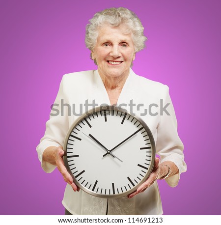 portrait of a happy senior woman holding clock over purple