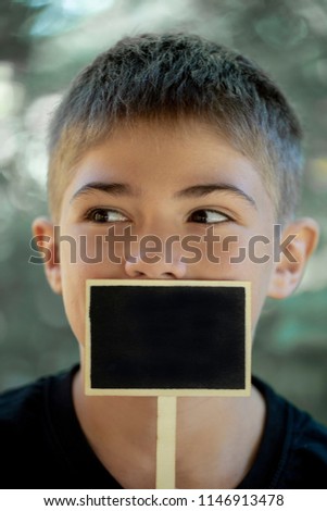 the youth's face close up,the teenager holds a black wooden sign at the mouth