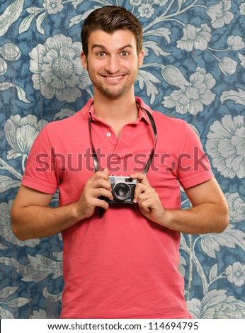 Portrait of a man holding camera on wallpaper