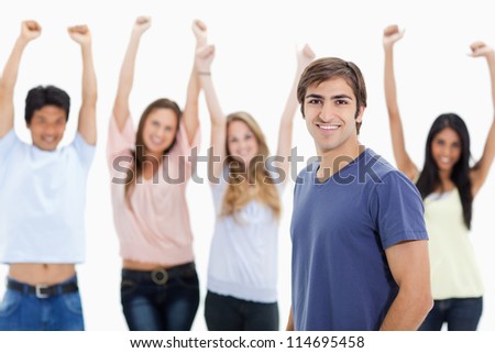 Smiling man with people behind him raising their arms against white background
