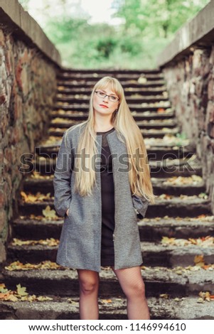 Outdoor portrait of a young caucasian woman with gorgeous long natural blondie hair posing in park in autumn leaves background