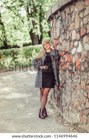 Outdoor portrait of a young caucasian woman with gorgeous long natural blondie hair posing in park in autumn leaves background