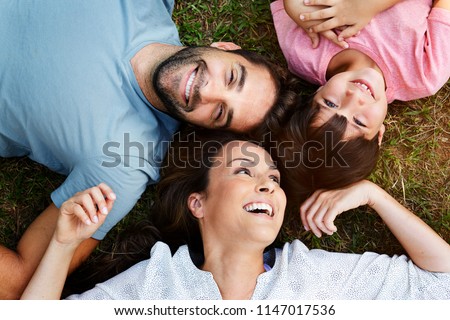 Mom dad and son lying together in park