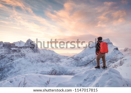 Tourist man climbs on top snowy mountain with colorful sky in morning