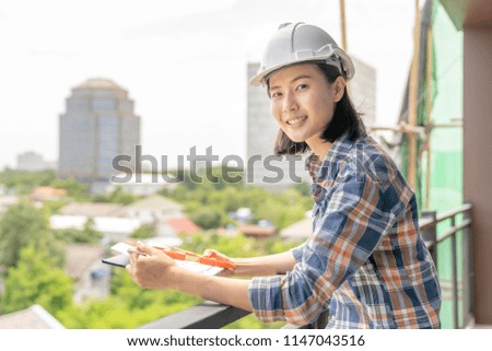 Asian woman civil engineer,architecture checking blueprint in tablet at working site.blue print is fake only for stock photo.
