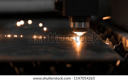 CNC fiber laser cutting the sheet metal with sparks light and bokeh