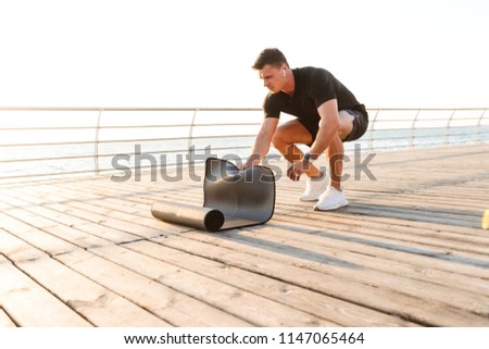 Image of handsome young sportsman outdoors on the beach with sport carpet.