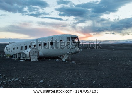Dusk picture of crashed plane on black volcanic beach in Iceland during midnight sun.