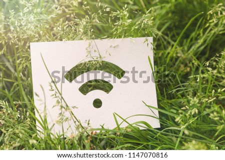 The Wi-Fi wireless network sign on a bright green grass. Internet in the park, convenient city, social networks.