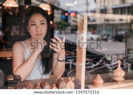Beautiful Asian women Using smart Phone with Cup of Tea Emotional happiness on table in cafe restaurant or coffee shop .Post to Social Network and Social Media Online Internet On table in holiday.