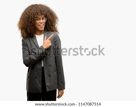African american business woman wearing glasses cheerful with a smile of face pointing with hand and finger up to the side with happy and natural expression on face looking at the camera.