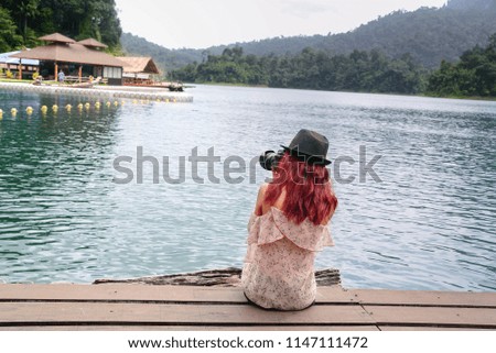 Young woman sitting take a photo near the lake in nature background.