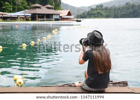 Young woman sitting take a photo near the lake in nature background.
