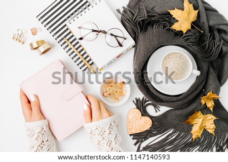 Workspace with notebook with empty card, coffee cup wrapped in scarf,  glasses. Stylish office desk. Autumn or Winter concept.  Flat lay, top view