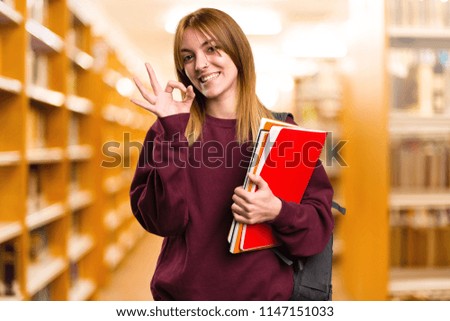 Student woman making OK sign on unfocused background