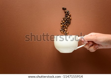Hand holding cup of coffee with smoke from coffee beans brown paper background. Top view. Flat lay. copy space. Good morning concept. Royalty-Free Stock Photo #1147155914