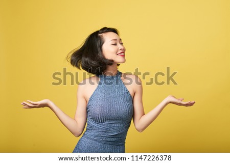 Joyful attractive young woman dancing against yellow background