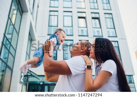 married couple, aman holding child, woman holding man on his shoulders. against background glass building