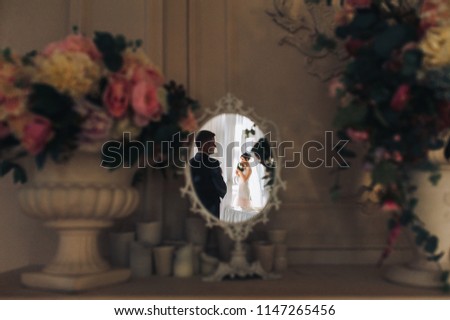 Beautiful newlyweds are reflected in the mirror. Silhouette of the newlyweds in the interior. Wedding idea. Wedding concept.