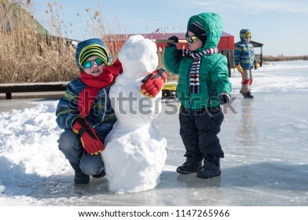 Happy boys in colorful winter clothes doing gymnastics on ice and snow. Glasses for skiing, snowboarding and sledging. child is playing outdoors in snow. Outdoor fun for winter holidays