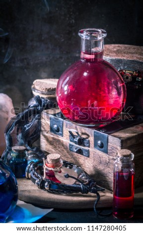 Magic concept. Red potion in bottle, candles, wooden box. Magical background